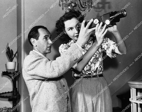 candid Lynn Bari & man use optical device for looking at negatives maybe - 11007-037