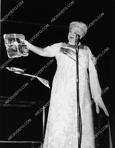 Sophie Tucker on stage holding up a tattered album cover I think 2334-07