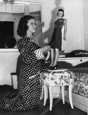 Shirley Temple in her dressing room fitting one of her dolls 5611a-14