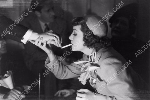 someone lights Claudette Colbert's cigarette 8b20-7751